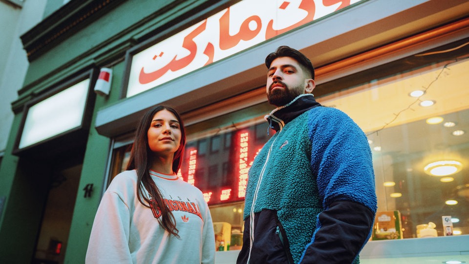 Meltem und Yousuf von Chai Society stehen vor einem Kiosk.